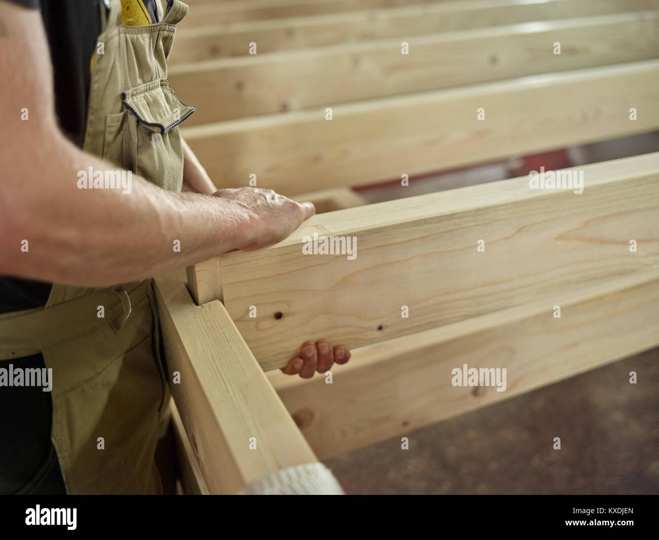 Gli uomini con le mani in mano collegare due travi di legno con scanalatura e linguetta di connessione di una costruzione in legno, Austria Foto Stock