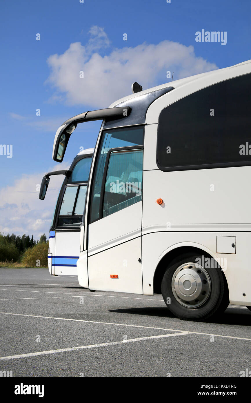 Due bianchi autobus autobus su parcheggio all'estate con cielo blu e alcune nuvole, vista verticale. Foto Stock