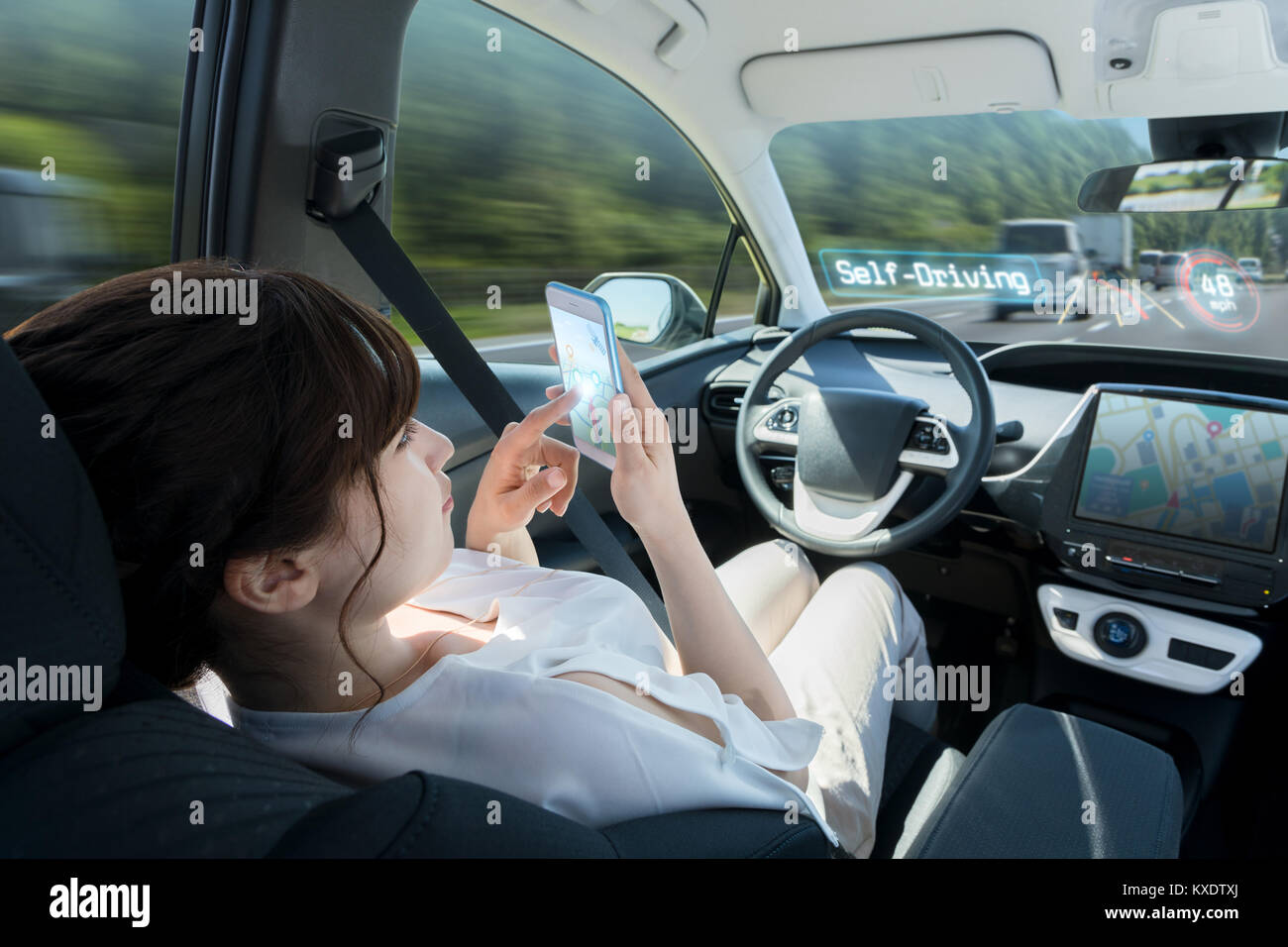 Donna che utilizza smart phone in auto autonoma. auto durante la guida del veicolo. driverless car. autopilot. tecnologia automobilistica. Foto Stock