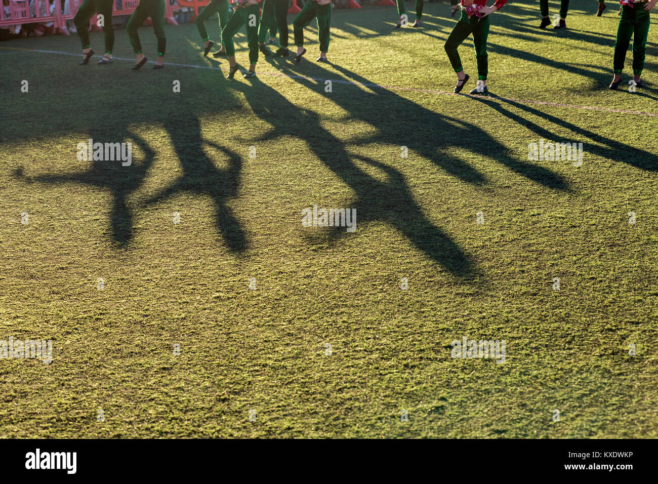 Ombre lunghe di ballerini in erba del campo di calcio in Adeje come il corpo di ballo di intrattenere la folla in attesa dell'arrivo dei tre re magi, T Foto Stock