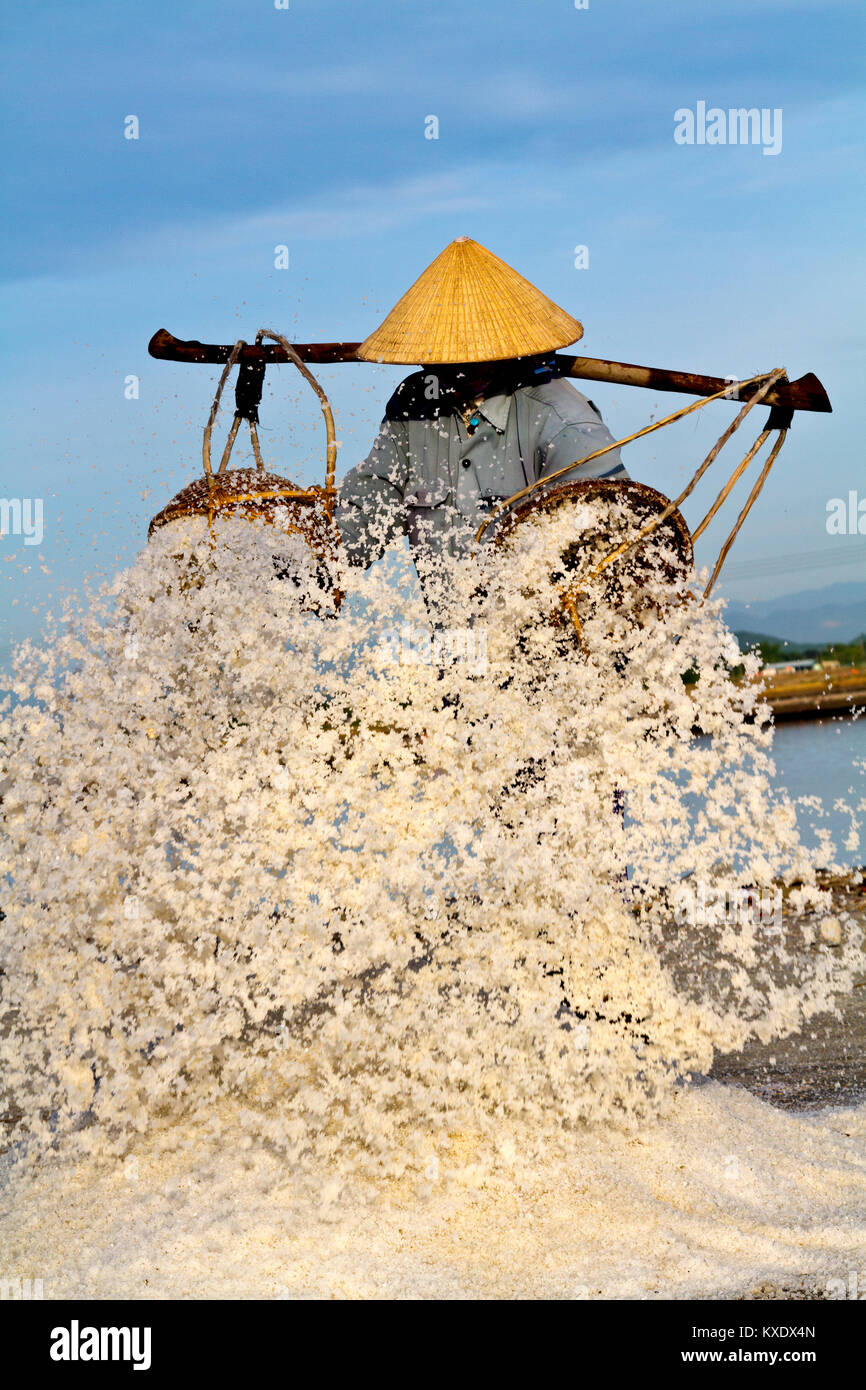 Sale femmina harvester lo svuotamento del suo sale pesanti cesti. Vicino a Doc Let, Vietnam. Iniziano a lavorare a lungo prima di sunrise, al fine di evitare la maggior parte del calore Foto Stock