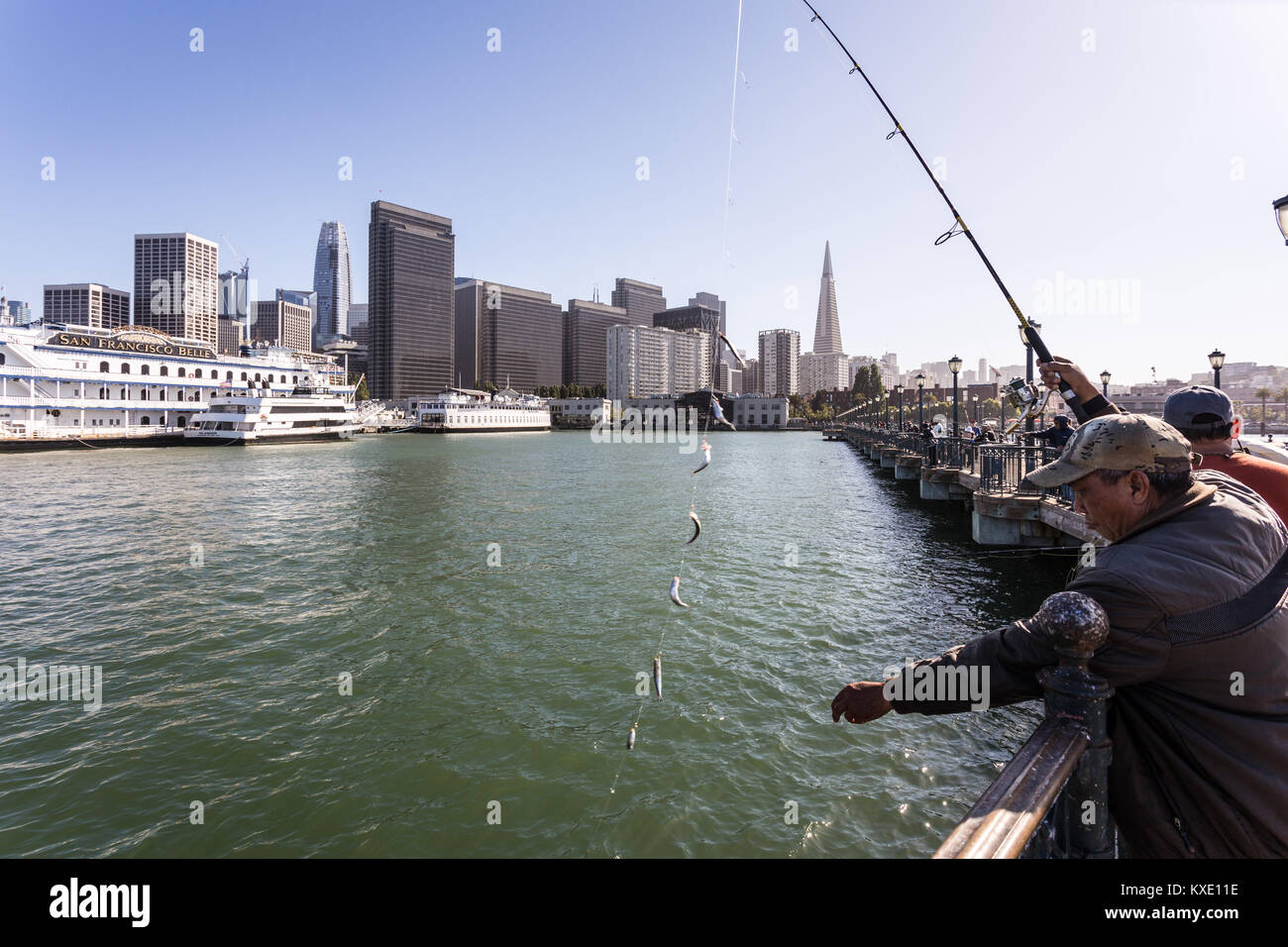 San Francisco, Stati Uniti d'America - 2 Luglio 2017: persone di pesca su un molo all'Embarcadero nel centro cittadino di San Francisco con il quartiere finanziario e il centro storico Foto Stock