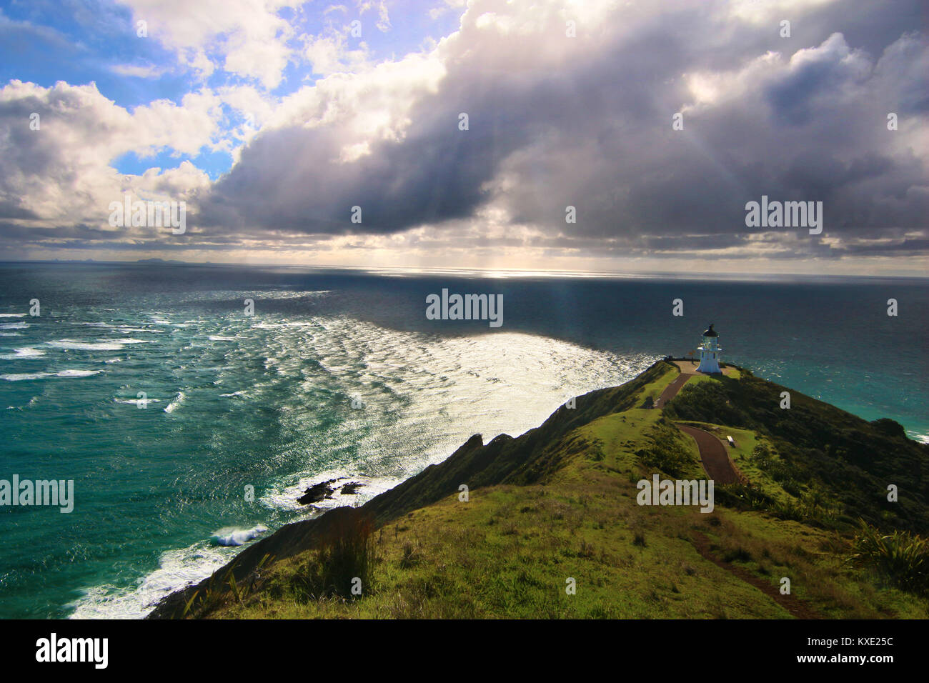 Il drammatico paesaggio di luce dell'Oceano Pacifico costa selvaggia con un faro sulla cima della roccia. Il punto più settentrionale di Cape Reinga, Nuova Zelanda Foto Stock