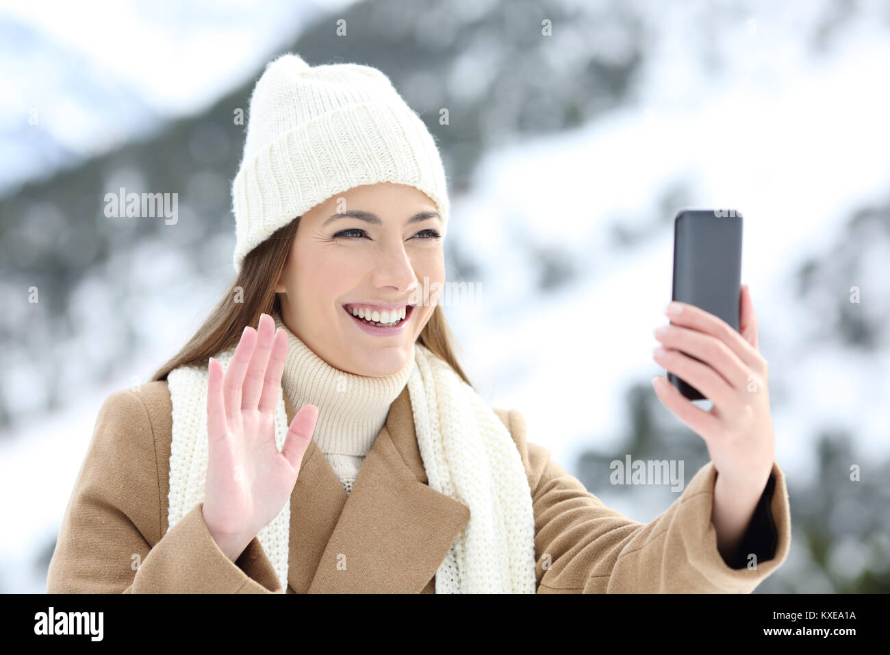 Felice tourist avente una chiamata video o prendendo un selfie in vacanze invernali in una montagna innevata Foto Stock