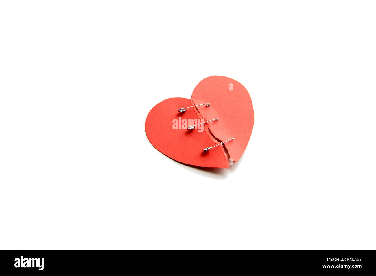 Cuore rosso con parti rotte fissata tramite perni isolato su bianco Foto Stock