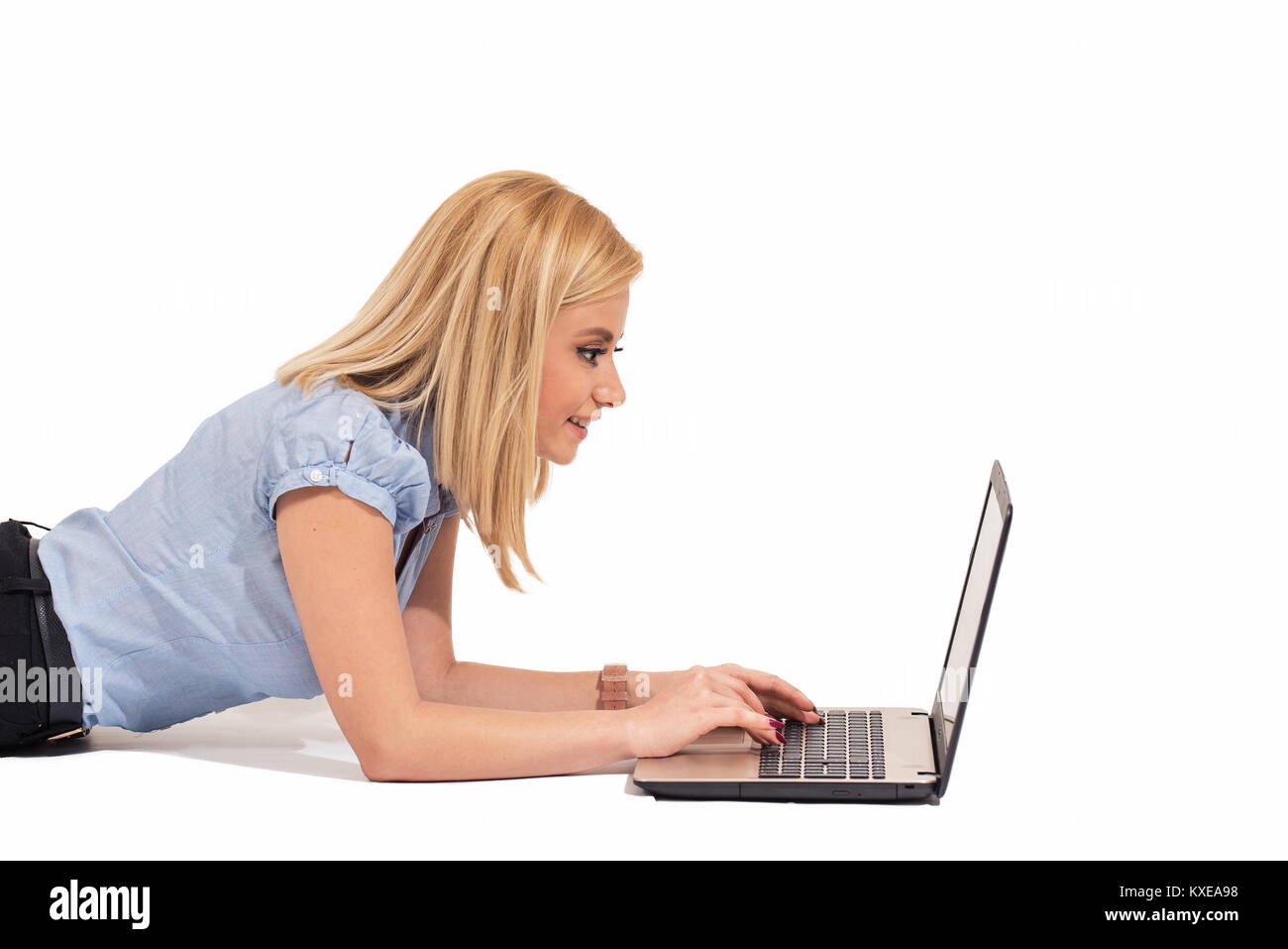 Giovane donna posa casualmente sul pavimento con il computer portatile Foto Stock