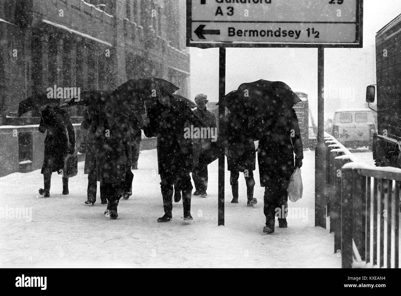 Città battaglia dei lavoratori attraverso la Blizzard a London Bridge. Foto Stock