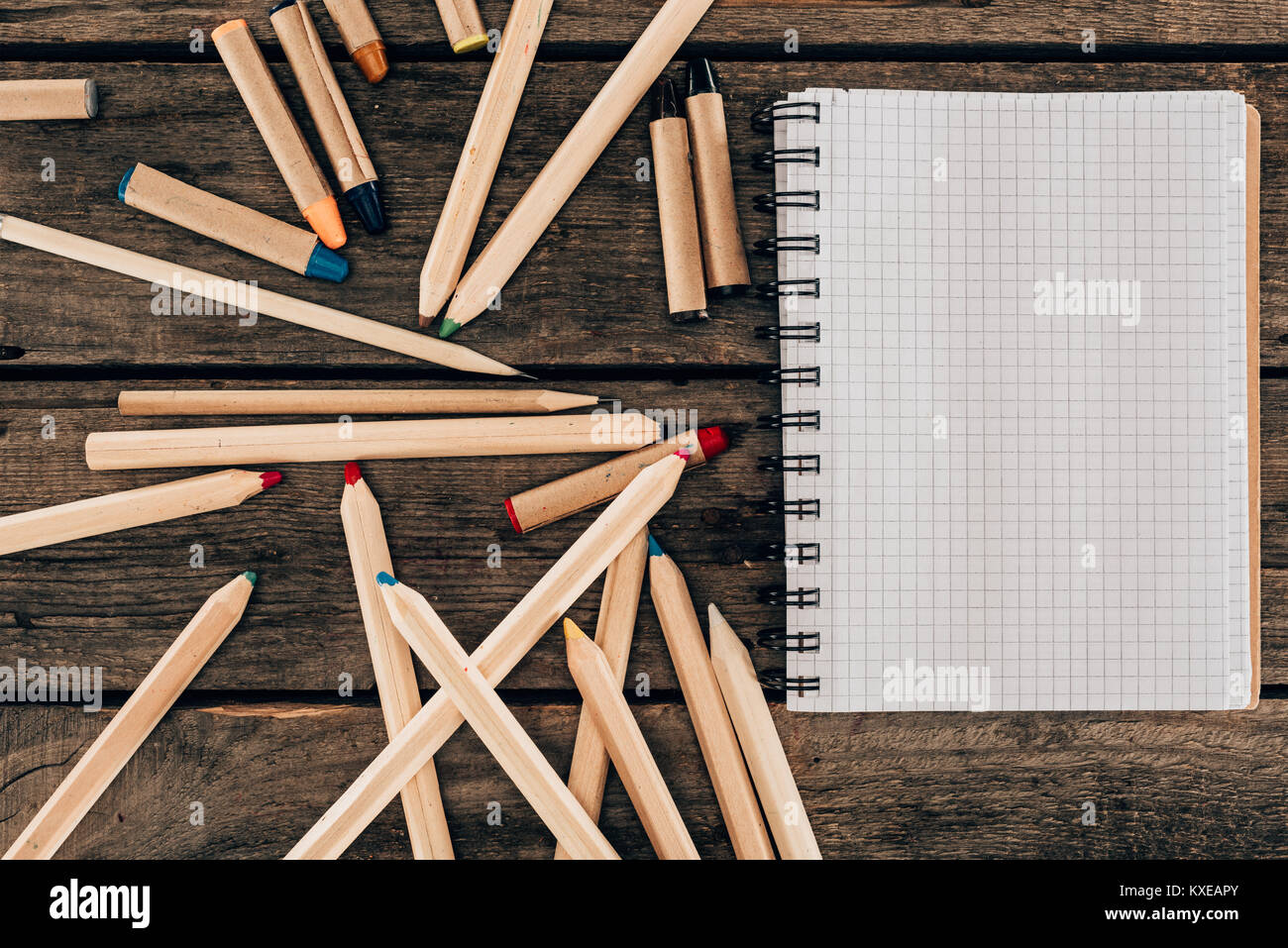 Vista superiore della composizione di matite colorate con notebook in bianco su sfondo di legno Foto Stock