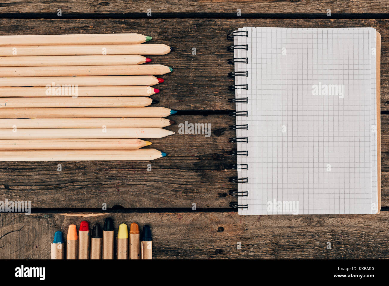 Vista superiore della composizione di matite colorate con notebook in bianco su sfondo di legno Foto Stock