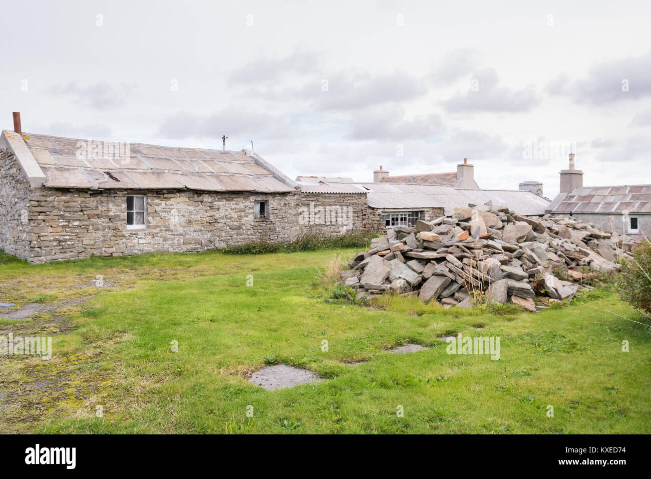Copertura spessa piastrelle o lastre di ardesia accanto alla tradizionale edificio in pietra con tetto in ardesia su Westray, Orkney Islands, Scotland, Regno Unito Foto Stock