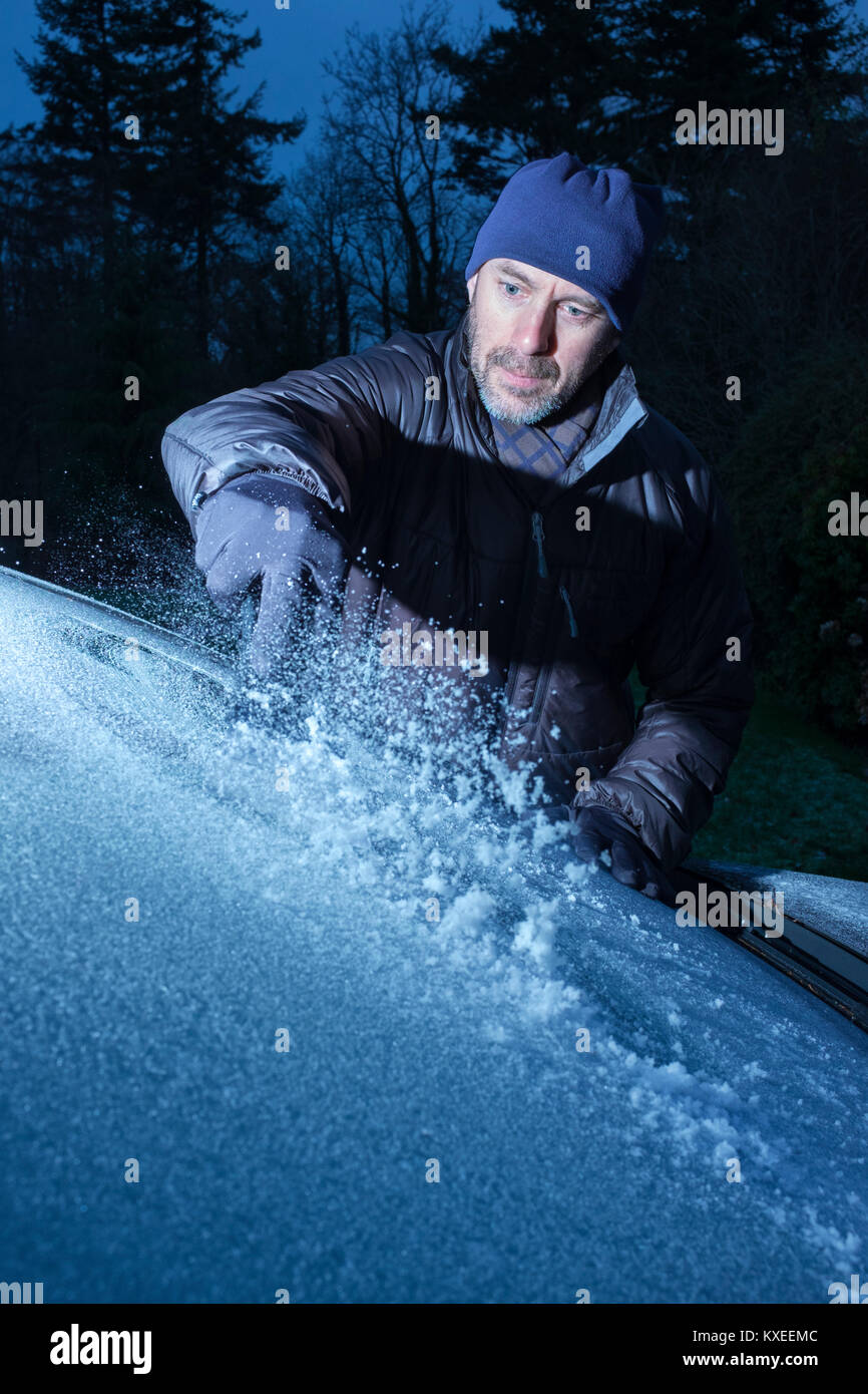 Un uomo di ghiaccio di raschiatura di un parabrezza di automobile. Foto Stock