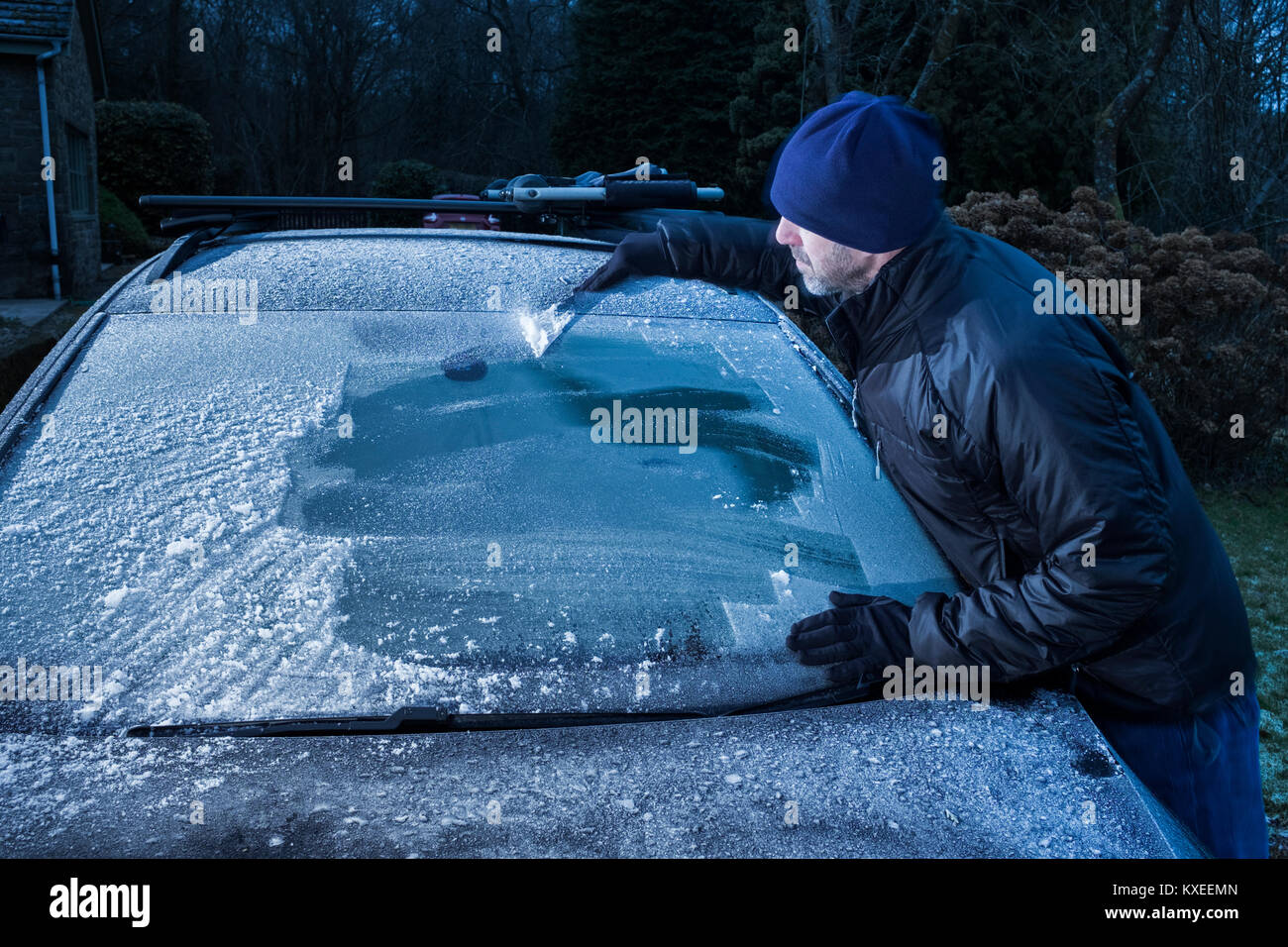 Un uomo di ghiaccio di raschiatura di un parabrezza di automobile. Foto Stock
