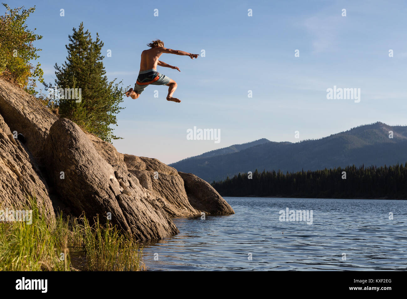 Un uomo balza in un lago in Boise National Forest. Foto Stock