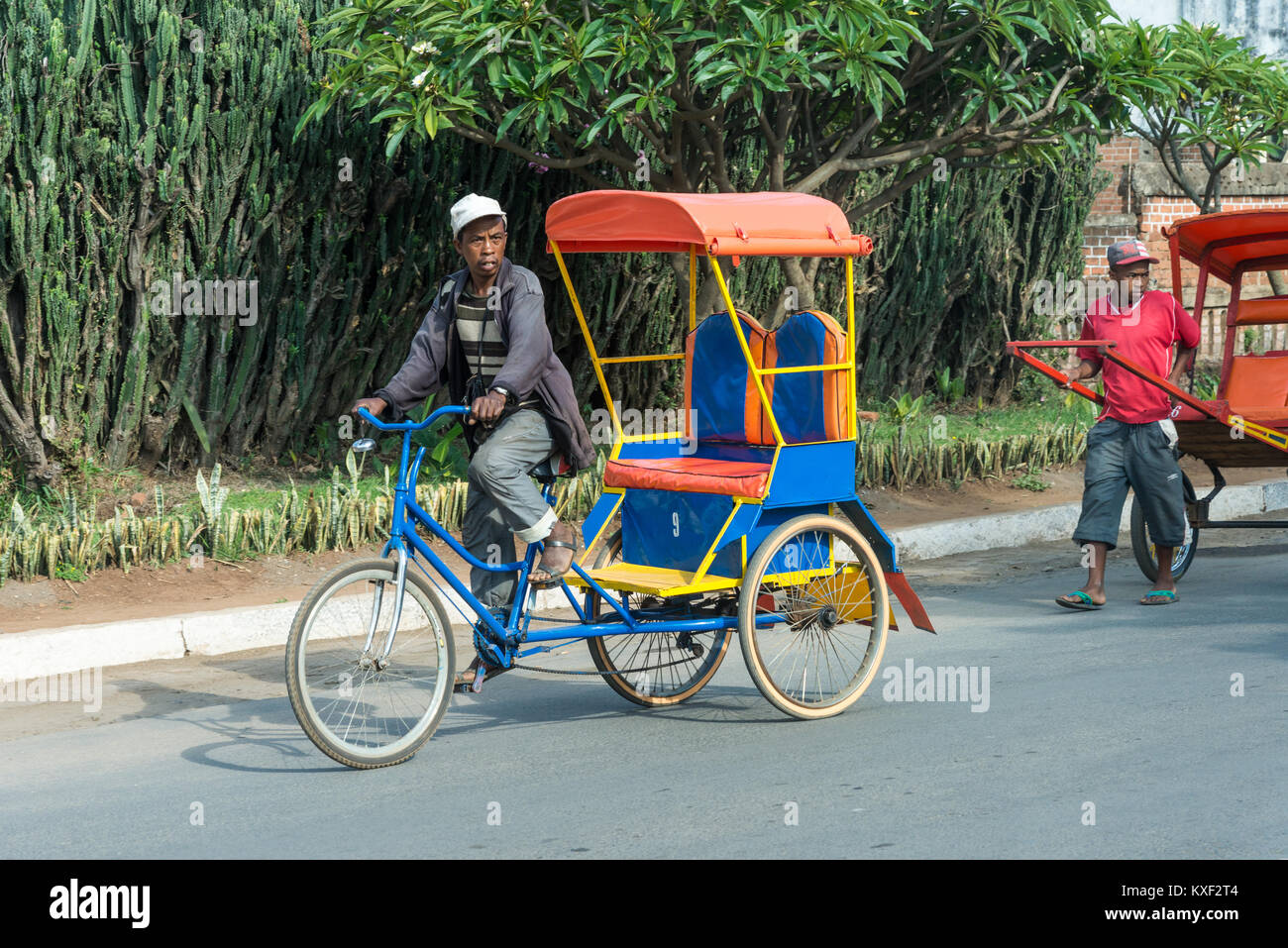 Un uomo sguazzare un rickshaw sulla strada della piccola città Antsirabe, Madagascar, Africa. Foto Stock