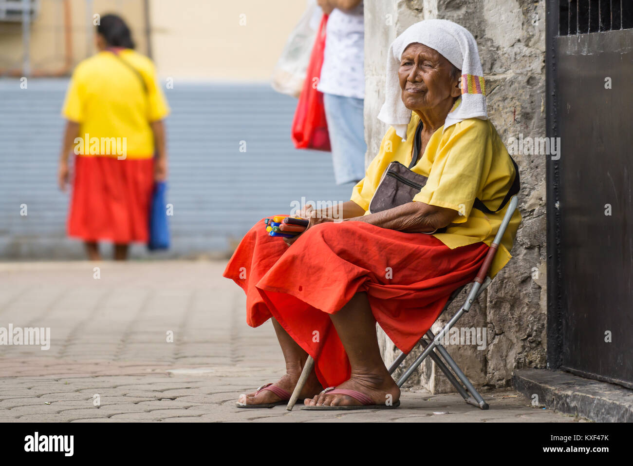 Donna anziana vendita di candele vicino alla costruzione di alloggiamento Croce Magellans,Cebu City Foto Stock