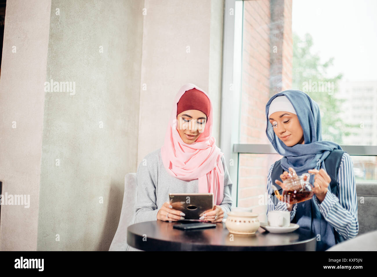 Musulmani femmina studente di college utilizzando computer tablet in cafe Foto Stock