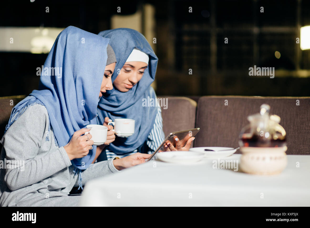 Bella donna musulmana utilizzano tablet in cafe Foto Stock