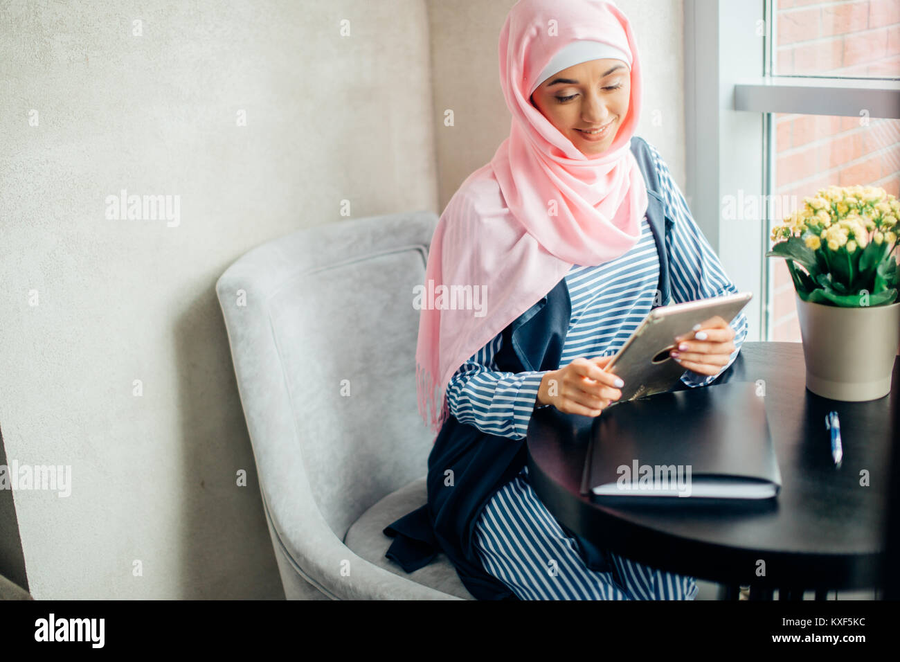 Musulmani femmina studente di college utilizzando computer tablet in cafe Foto Stock