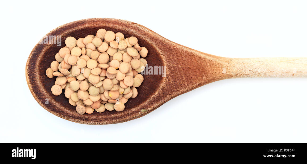 Materie lenticchie in un cucchiaio di legno su sfondo bianco Foto Stock