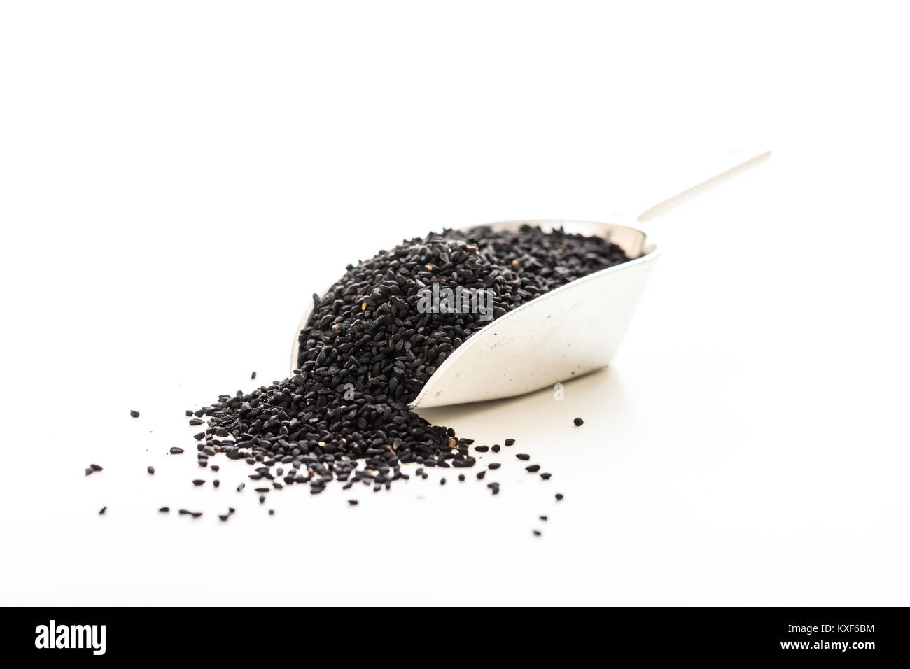 Sesamo nero in un convogliatore metallico su sfondo bianco Foto Stock