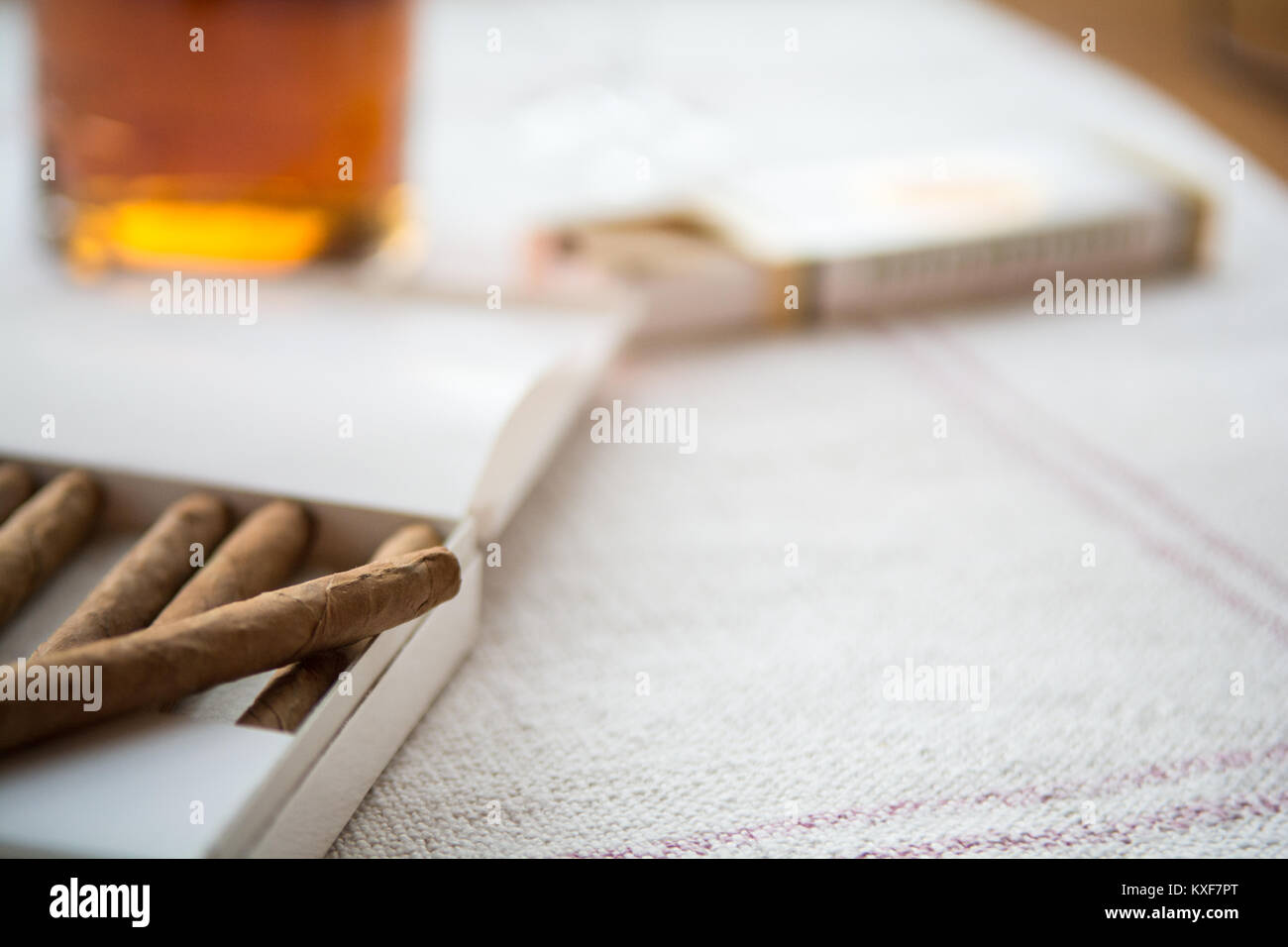 Sigari e whiskey su un tavolo luminoso panno, un sigaro fuori del pacchetto Foto Stock