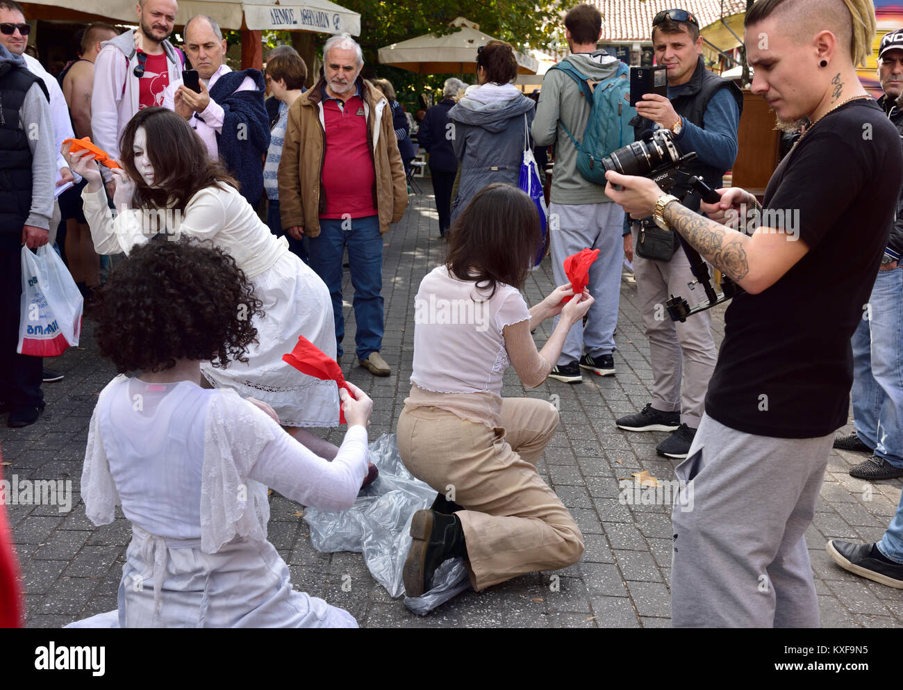 Street performance ad Atene in piazza del mercato, le donne in bianco, gli astanti con telecamere Foto Stock