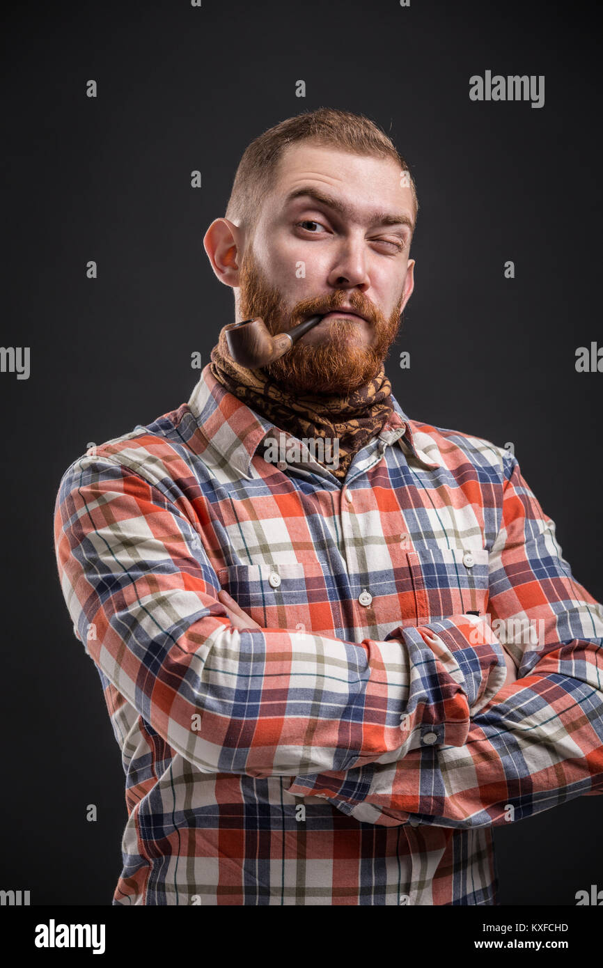Ritratto di uomo barbuto tubo di fumo con occhio squinted Foto Stock