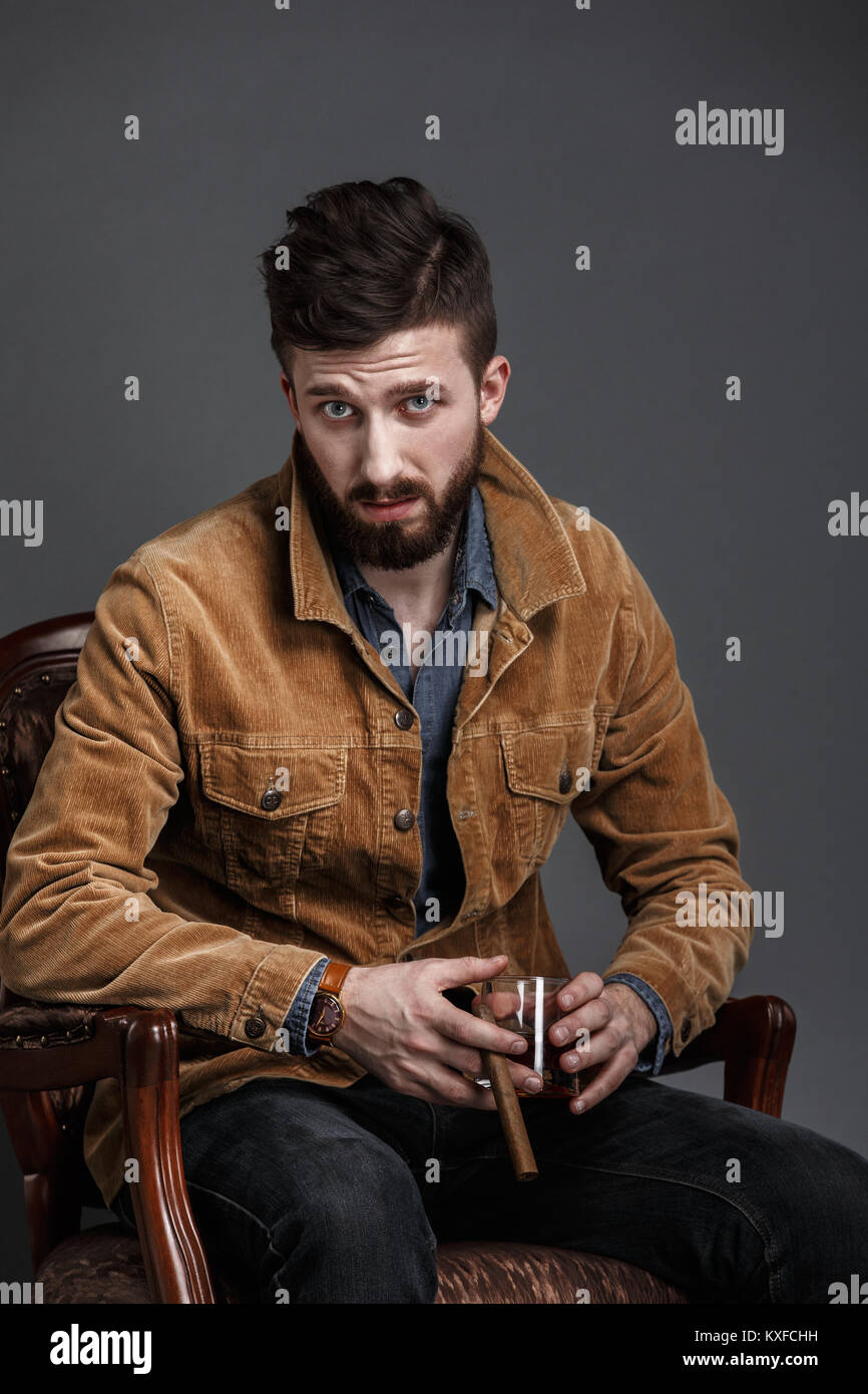 Ritratto di grave uomo barbuto con sigaro e whisky Foto Stock