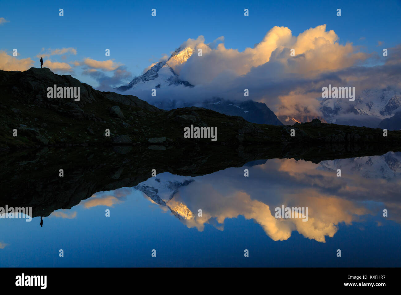 Un escursionista godendo le montagne e nuvole riflettono in Lac De Chéserys, Chamonix, Francia. Foto Stock