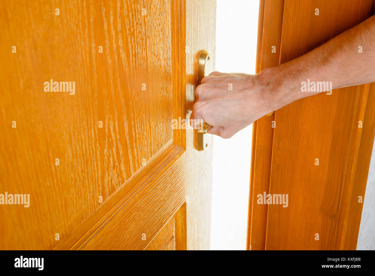 Un uomo è l'apertura di una porta di legno con un manico metallico a uscire da una camera e inserire in una accesa. Foto Stock Un uomo è l'apertura di una porta di legno con un manico metallico a uscire da una camera e inserire in una accesa. Foto Stock