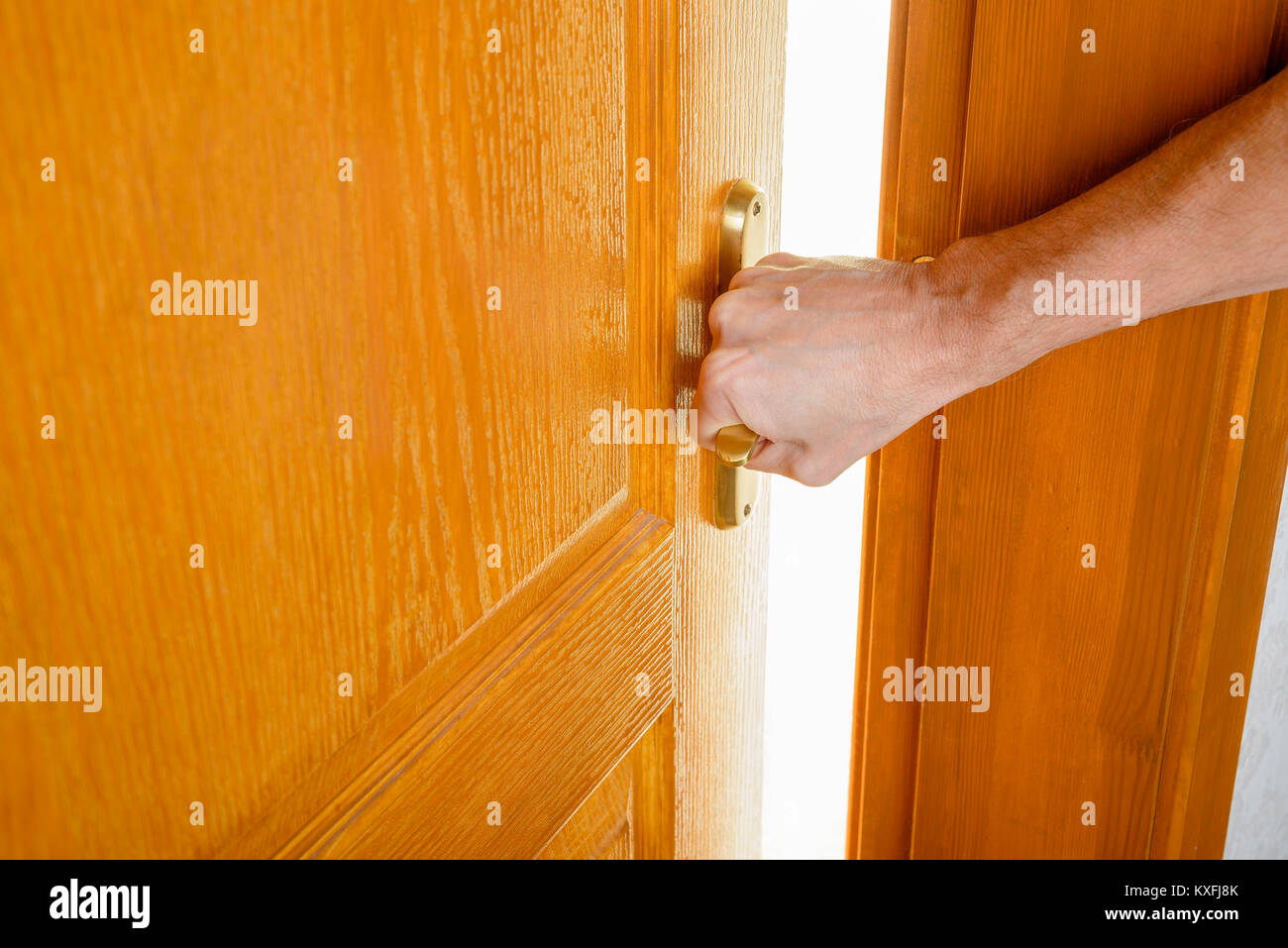 Un uomo è l'apertura di una porta di legno con un manico metallico a uscire da una camera e inserire in una accesa. Foto Stock Un uomo è l'apertura di una porta di legno con un manico metallico a uscire da una camera e inserire in una accesa. Foto Stock