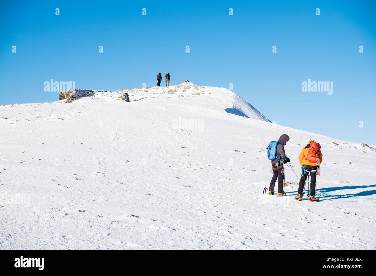 Gli alpinisti sul Vertice di Helvellyn Mountain Range in inverno, Lake District, Cumbria, Inghilterra. Foto Stock