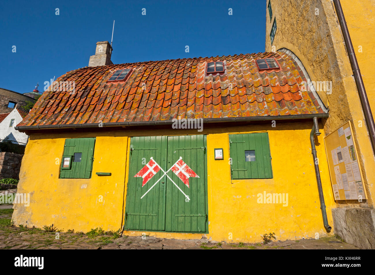 Cancello verde, bandiere danese, curvo tetto con tegole rosse sul Bohlendachhuset, Christiansø, Ertholmene, Bornholm, Danimarca Foto Stock