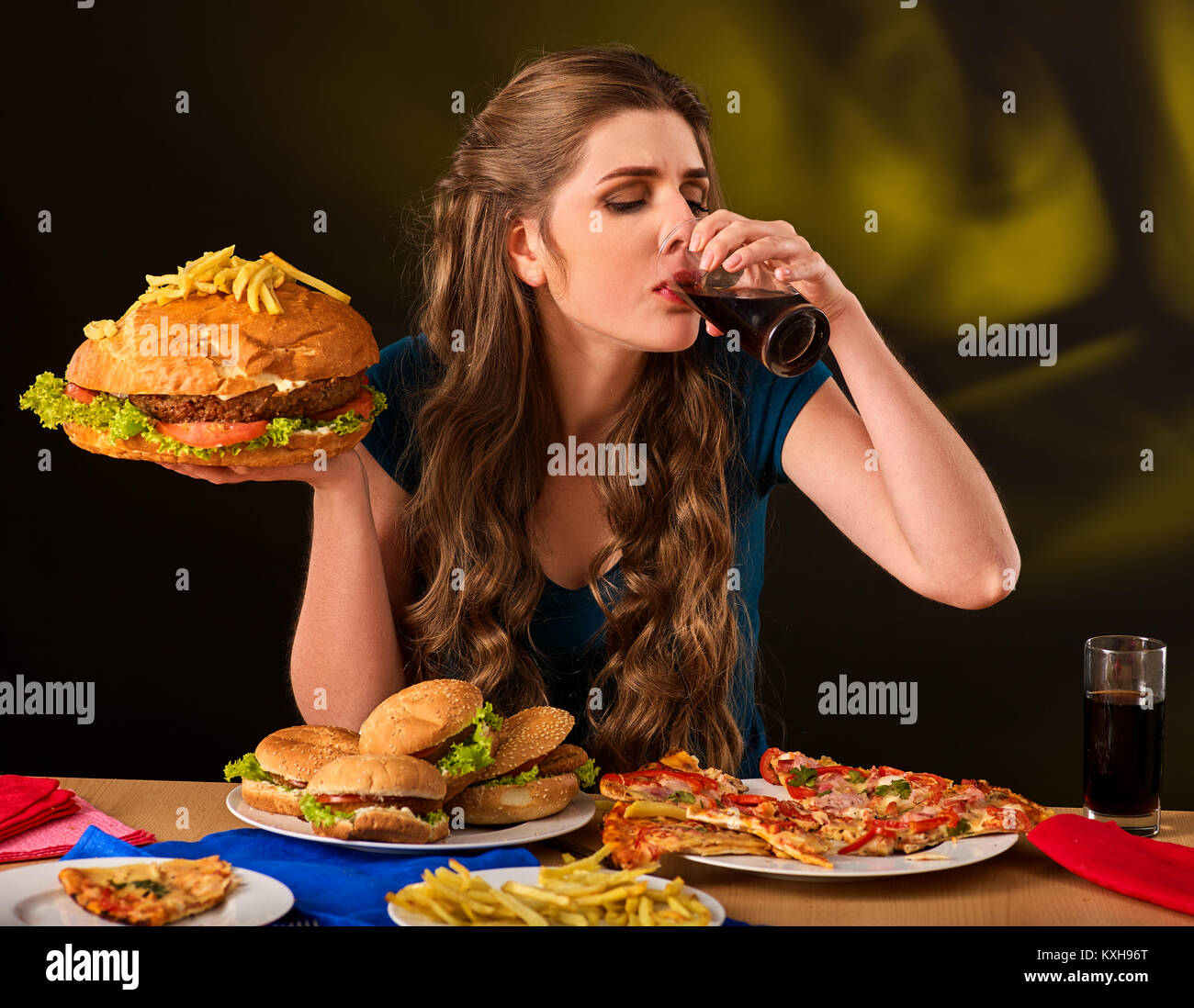 Donna di mangiare patatine e hamburger sul tavolo. Foto Stock
