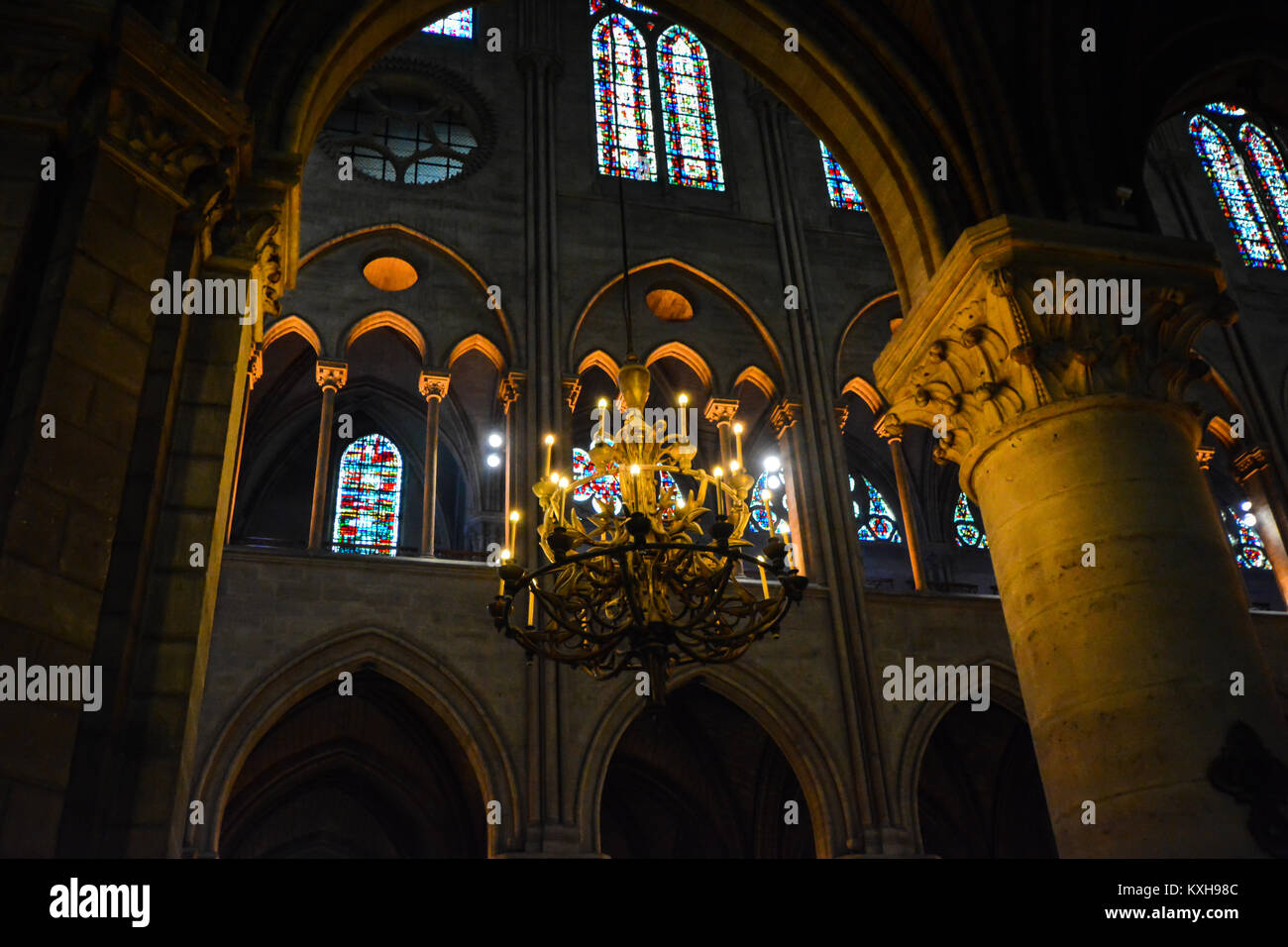 Il gotico, il buio interiore della cattedrale di Notre Dame a Parigi Francia con finestre di vetro macchiate con soffitti a volta e pareti un lampadario Foto Stock