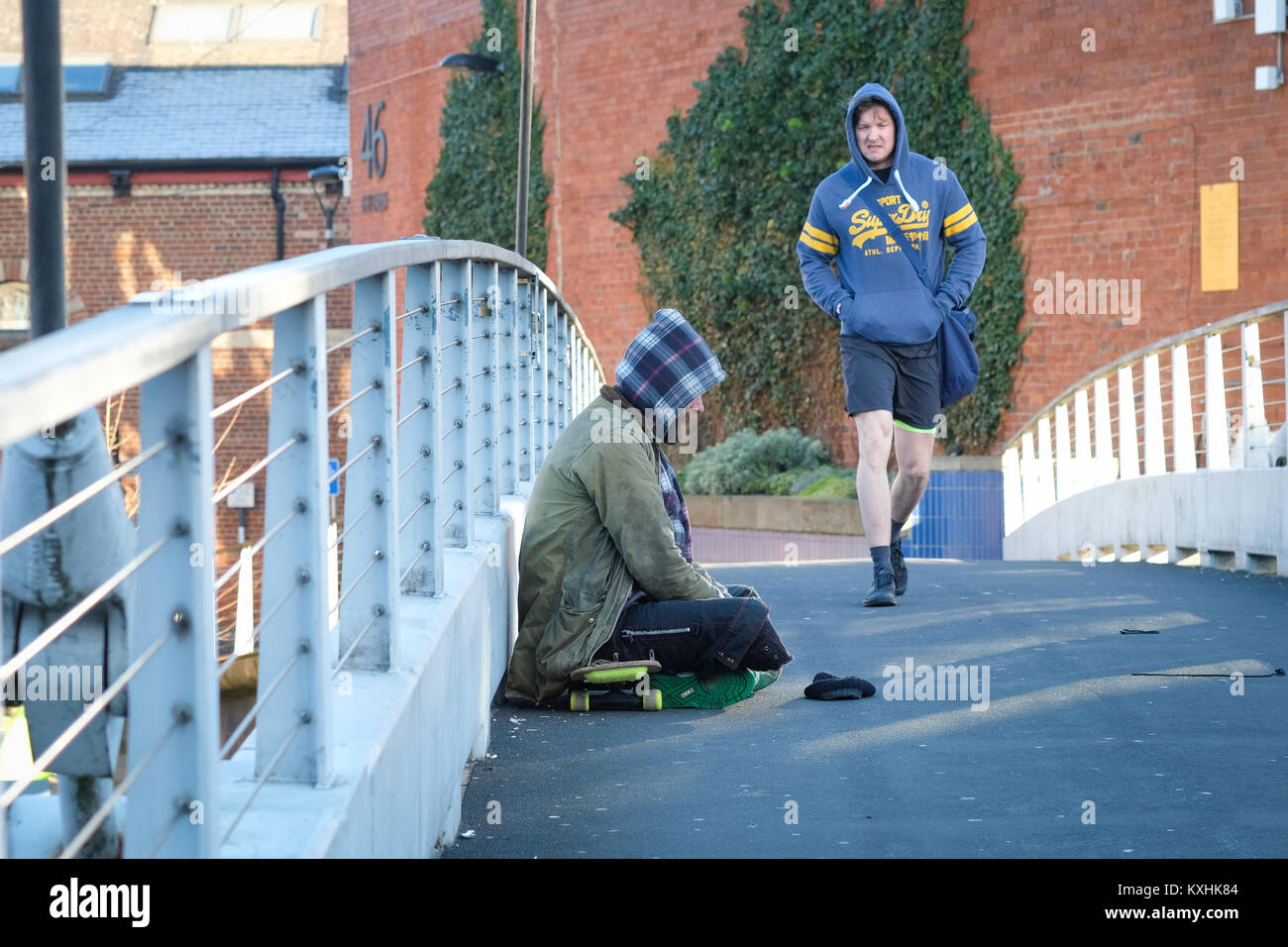Un senzatetto mendica sul ponte centenario, Leeds, Regno Unito in inverno, come pendolari di passaggio. Regno Unito crisi di alloggiamento 2018. Il divario sociale. Foto Stock