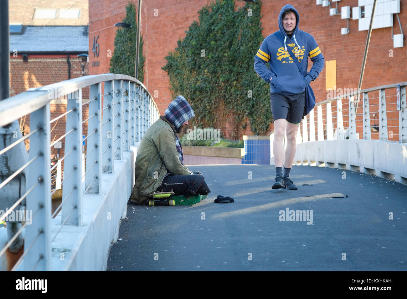 Un senzatetto mendica sul ponte centenario, Leeds, Regno Unito in inverno, come pendolari di passaggio. Regno Unito crisi di alloggiamento 2018. Il divario sociale. Foto Stock