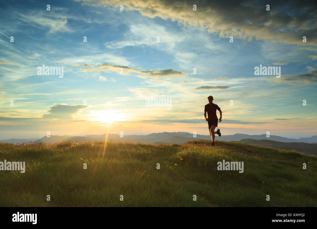 Atleta trailrunning in montagna durante un bel tramonto. Con motionblur. Foto Stock