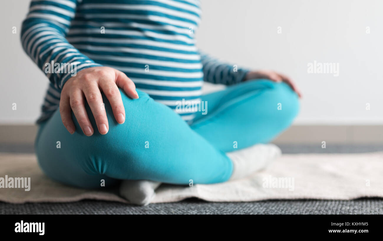 Donna incinta a praticare yoga esercizio a casa. Gravidanza yoga e fitness interni concetto. Ungraded basso contrasto riprese con finestra naturale luce. Foto Stock