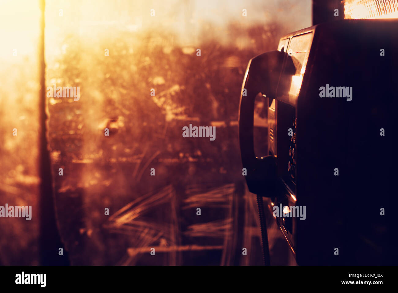 Telefono pubblico sulla strada phone booth nel tramonto, grungy la tecnologia di comunicazione con uno sfondo con spazio di copia Foto Stock