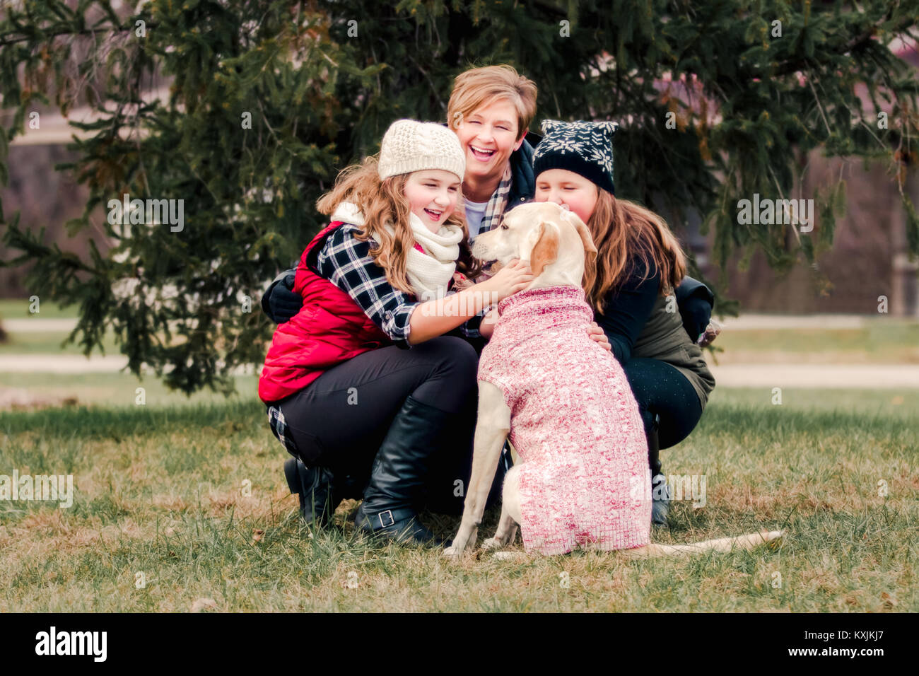 Sorelle e la loro madre accovacciato al cane in giardino Foto Stock
