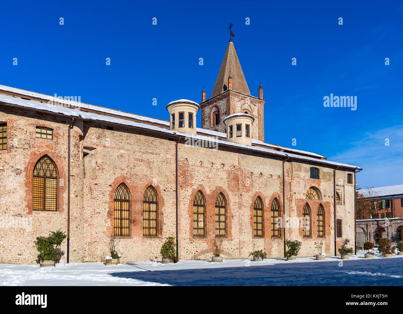 Snowy street e la vecchia chiesa sotto il cielo blu a Cuneo, Piemonte, Italia settentrionale. Foto Stock