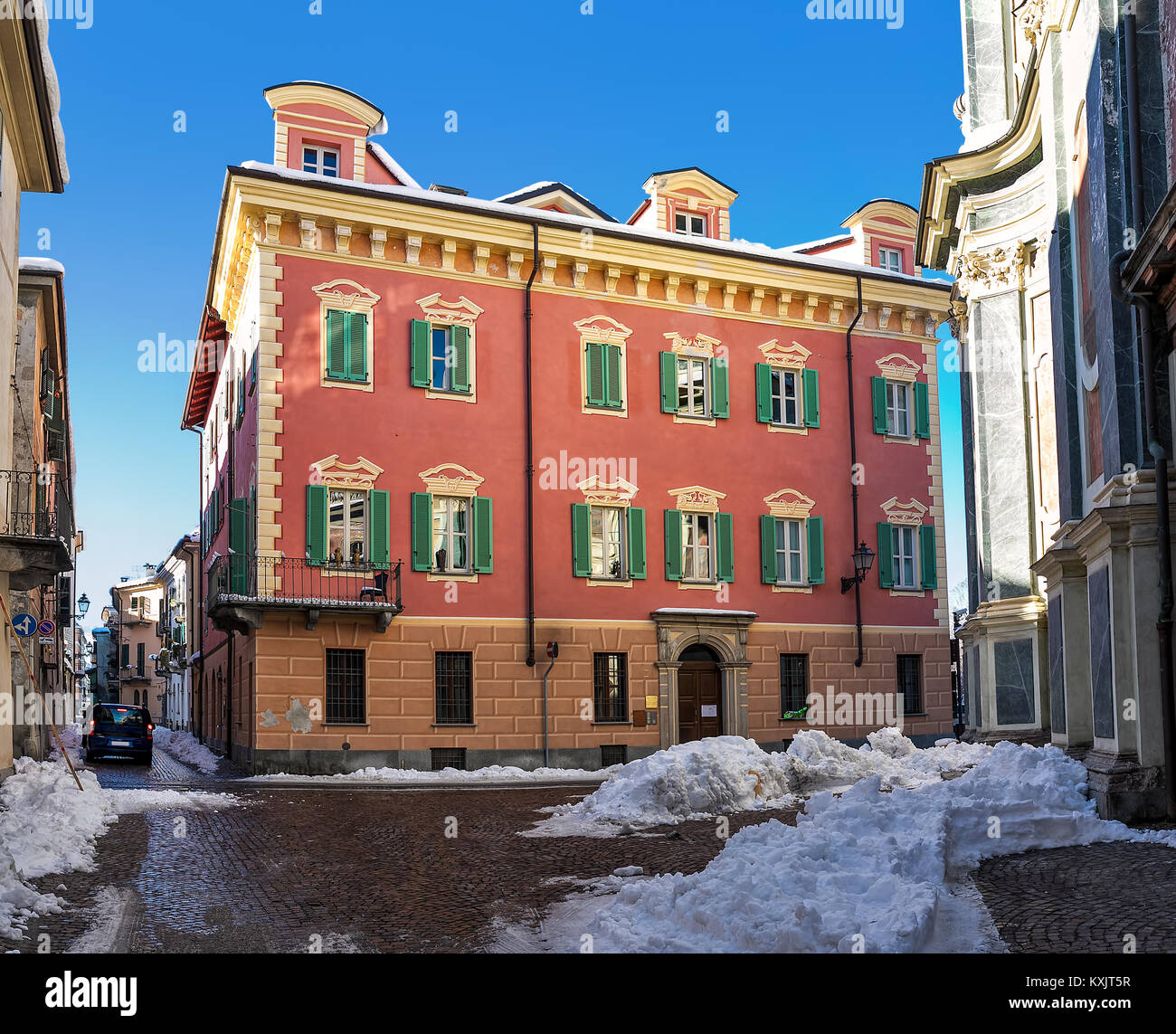 Tipico edificio colorato sulla stretta strada di ciottoli con neve nella città di Cuneo in Piemonte, Italia settentrionale. Foto Stock