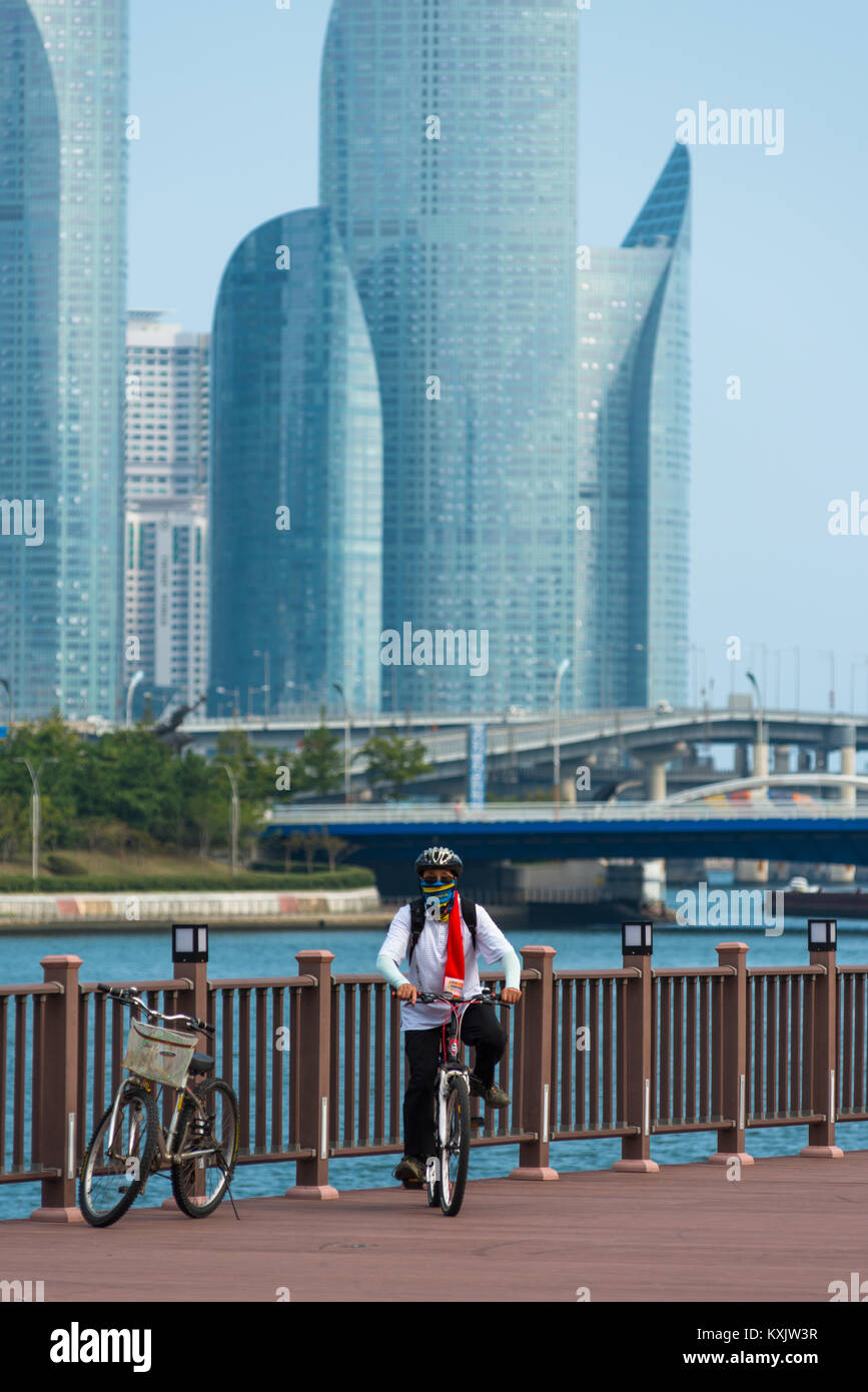 Corea del Sud ciclista di fronte fiume Suyoung con Centum park towers per la parte posteriore. Busan, Corea del Sud. Foto Stock