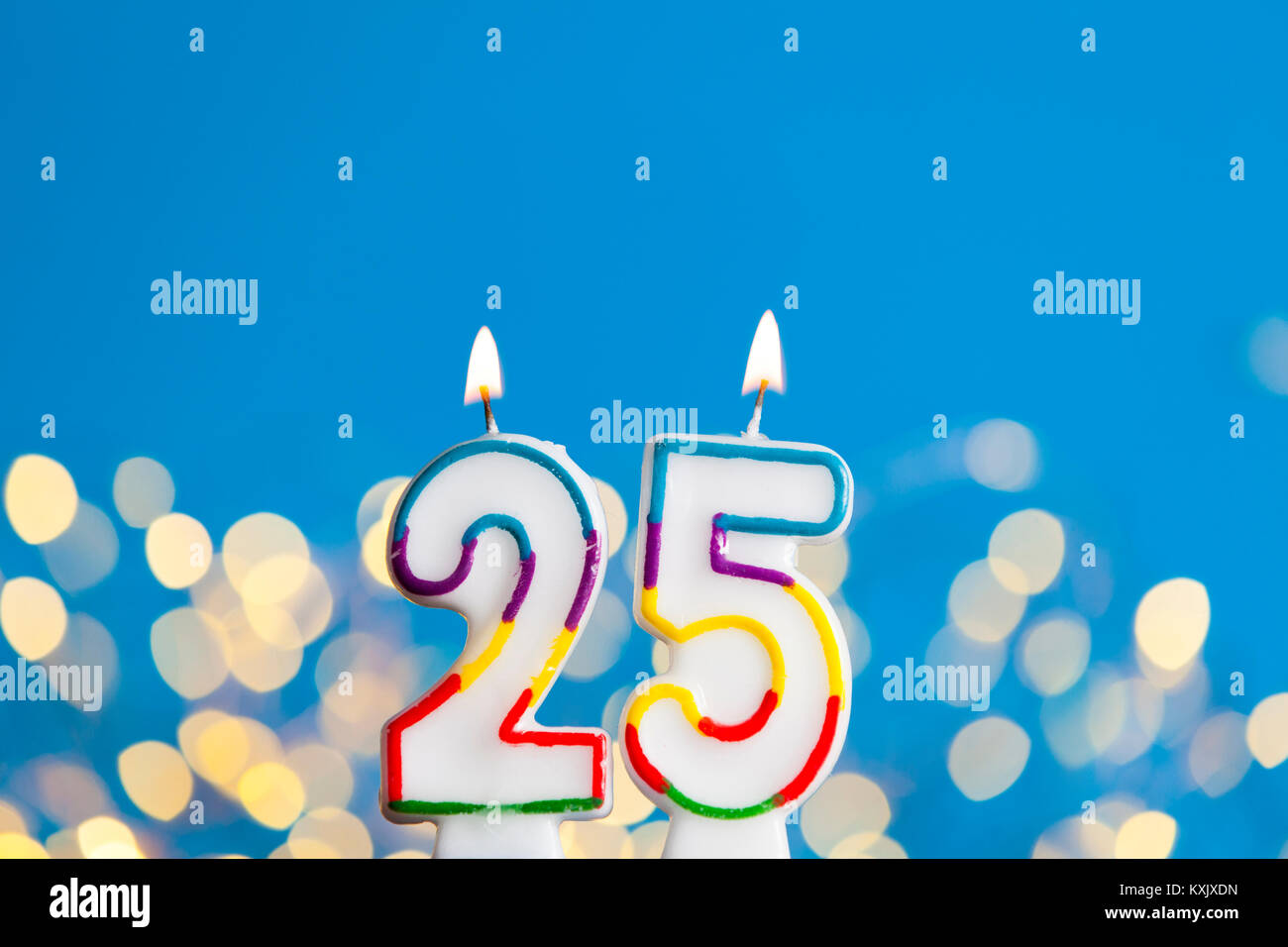 Numero 25 celebrazione di compleanno candela contro un luci luminose e sfondo blu Foto Stock