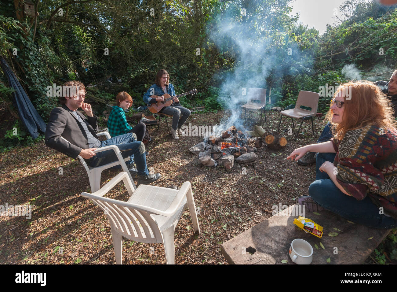 Un piccolo gruppo di persone erano seduti attorno a un fuoco di legno a parlare su un bel pomeriggio durante il crescere dell'aeroporto di Heathrow, la festa della mietitura. Foto Stock