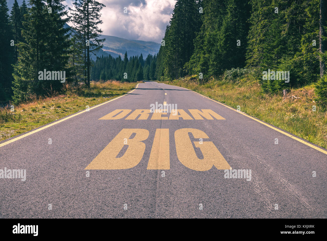 Strada asfaltata in montagna andando dritto fino a sognare in grande messaggio di testo. Concettuale la motivazione di business dello sfondo. Foto Stock