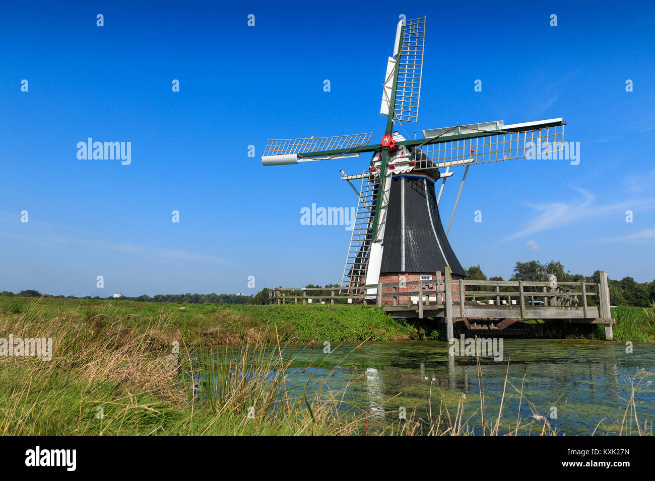 Storico mulino in acqua paesaggio. Mulino a vento De Helper vicino a Haren Groningen nei Paesi Bassi. Foto Stock