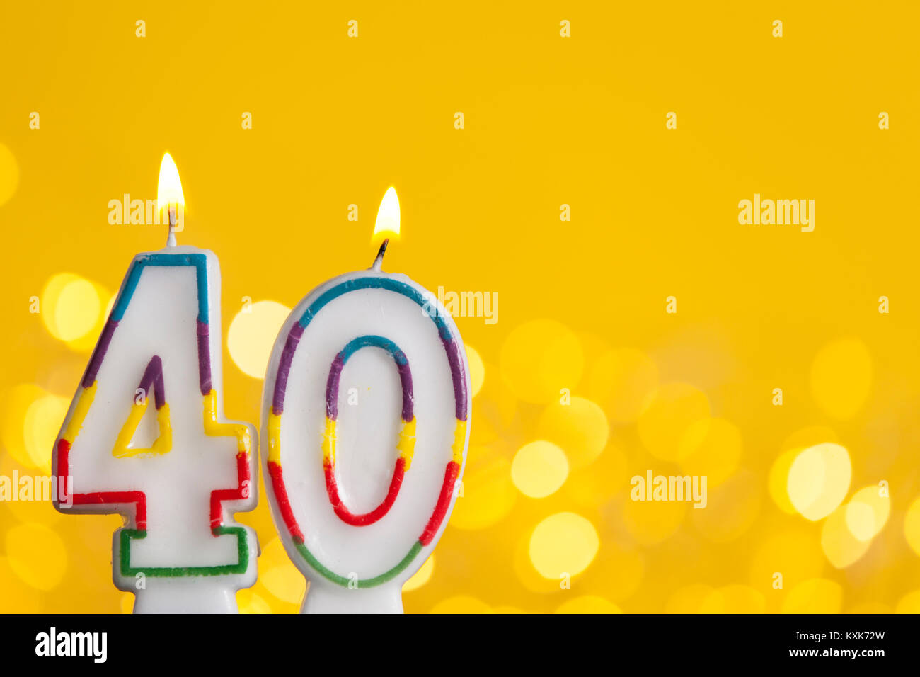 Numero 40 celebrazione di compleanno candela contro un luci luminose e sfondo giallo Foto Stock
