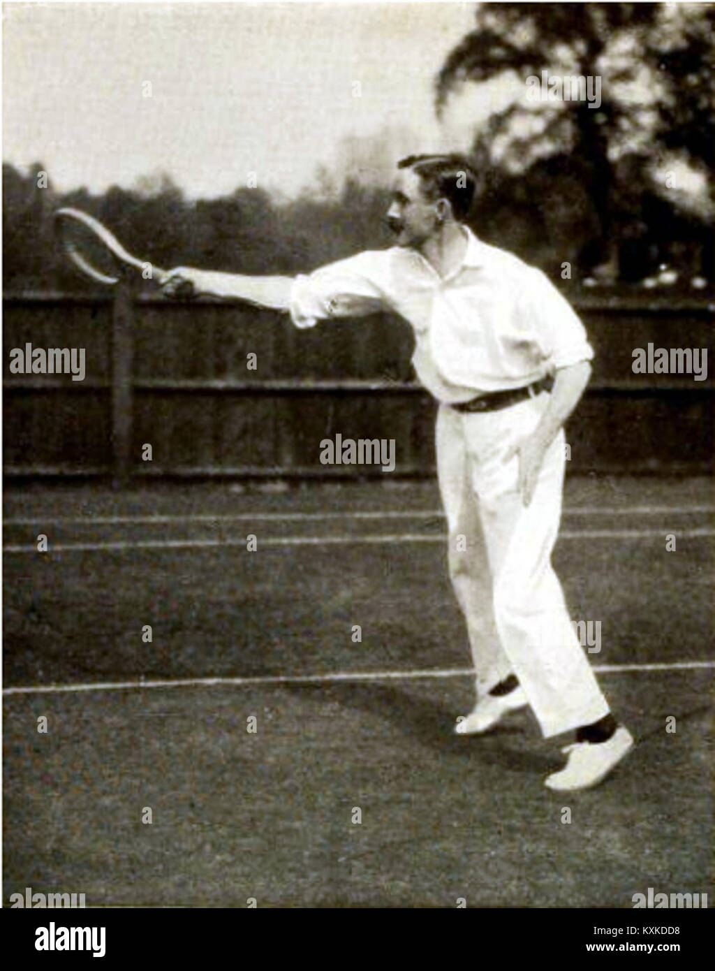 Arthur William Gore, un rinomato tennista, è raffigurato mentre esegue un colpo di prima mano durante una partita, dimostrando la sua abilità e tecnica atletica nel tennis all'inizio del XX secolo. Foto Stock
